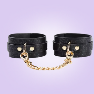 A close up of the wrist cuffs, the detachable gold chain is shown, this chain is removable.