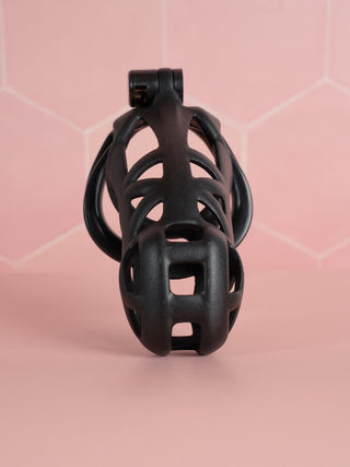 The black Cobra Double Cuff Cock Cage, it is shown from the front, the cut out design allows for air flow and urination.
