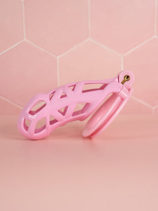 The Cobra Double Cuff Chastity Kit is shown from the side, the pink cage is shown with its base ring and integral lock fitted.