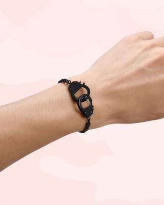 Gun Metal Black bracelet with a unique opening handcuff design worn on a wrist against a light pink background