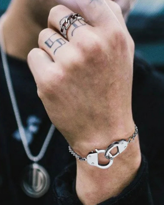 Hand wearing the silver Cuban Design Handcuff bracelet with a clasp design, with tattoos on the fingers.