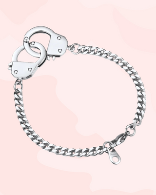 Silver handcuffs bracelet on a pink gradient background