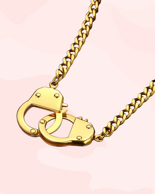 Gold handcuff necklace on a pink background