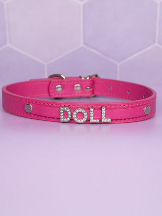 The pink leather collar with DOLL in rhinestone lettering sitting prominently on a matching pink strap.