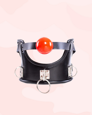 Black leather collar with a red ball gag and silver rings on a light pink background