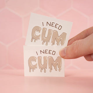 An alternate image of two I Need Cum tattoos, to show that each tattoo is the same.
