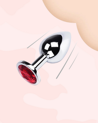 Jewelled anal plug with red accent on a light pink background