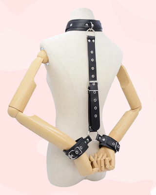 Black leather harness fully assembled on a mannequin with a pink background