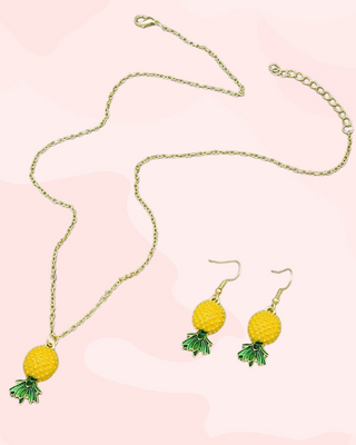 Pineapple-themed necklace and earrings on a pink background