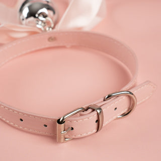 A close up of the silver buckle closure and pink PU leather collar on the satin soft bow collar.