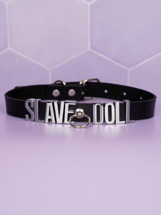 A close up view of the Slave Doll Slimline  Choker lying on a flat surface, the O Ring hook can be seen in the centre.