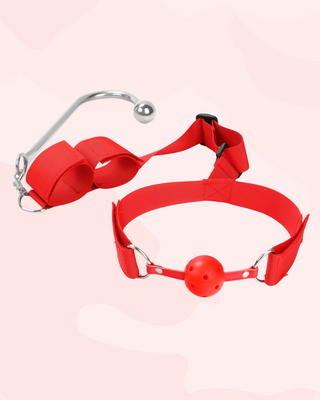 A close up of the red ball gag with breathable air holes, the adjustable velcro straps for the gag can be seen up close.