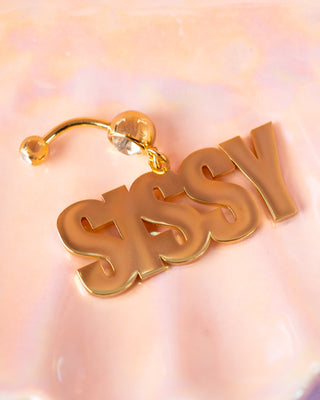 Sissy navel piercing in gold laid out flat.