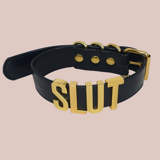 A close up of the black Slut collar with gold lettering.