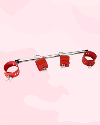 The padlock and keys are shown attached to the wrist and ankle cuffs on the spreader bar. All four can be individually locked.
