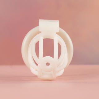 A front on view of the chastity cage in white, you can see the circular hole on the end of the cage that allows for a piercing.