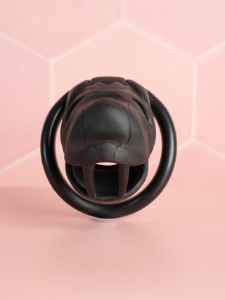 A front on view of the Serpent Sentry chastity cage, the base of the cage looks like an open serpent mouth, the cut out design allows for urination, air flow and cleaning.