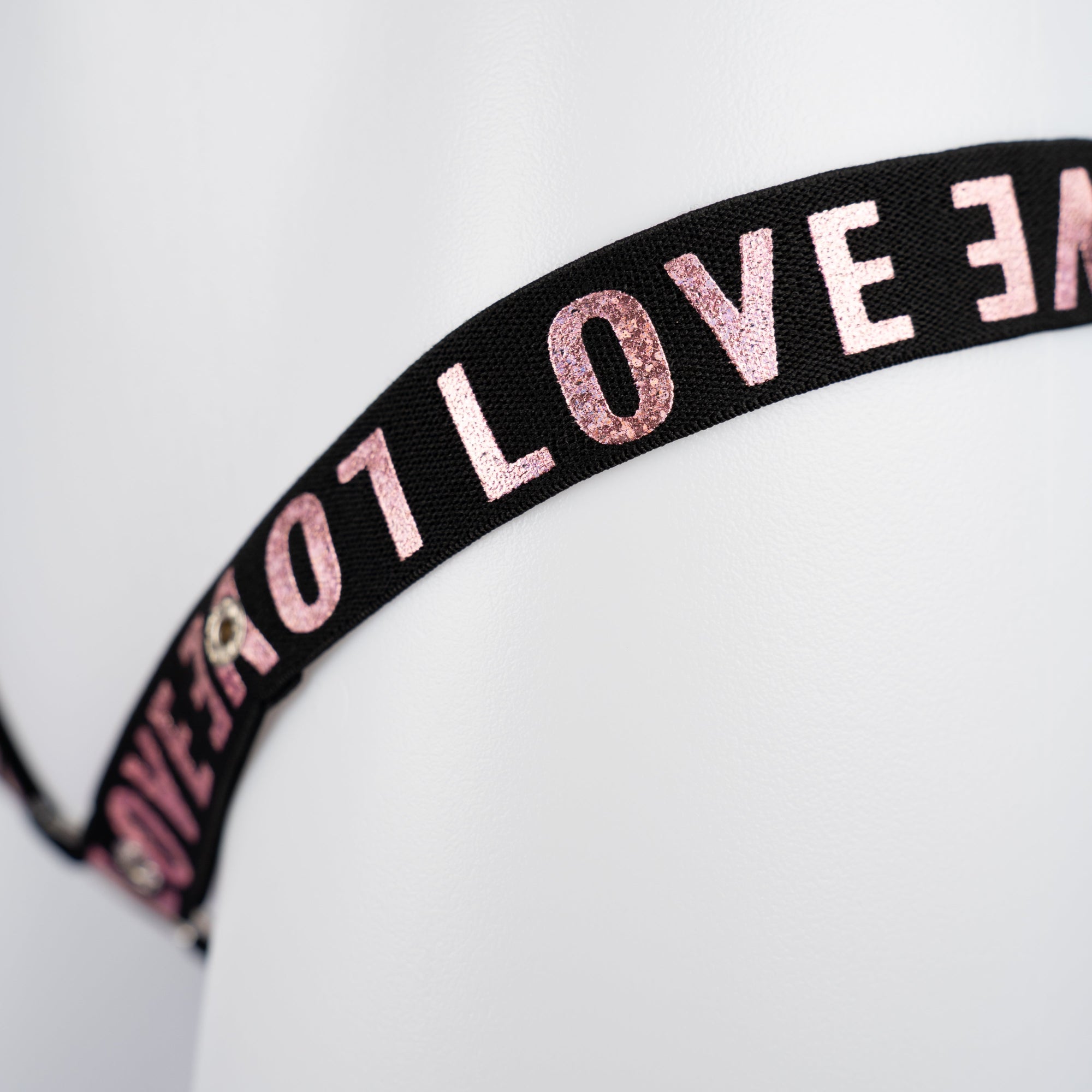 A close up of the LOVE lettering in pink on the 3 Way Restraining Chastity Belt