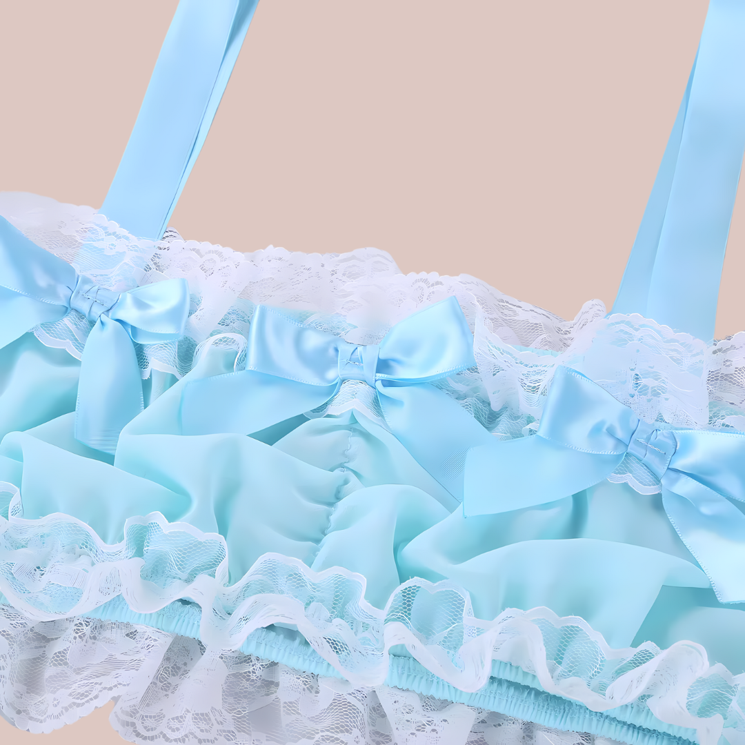 A close up of the baby blue bandeau style bra top, showing the ruched design, lace edging, satin bows and satin shoulder straps.