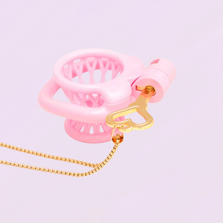 The Captivate Key in gold shown placing the lock into The Vessel chastity cage.