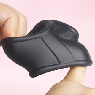 The cock ring being held and stretched on a pink background