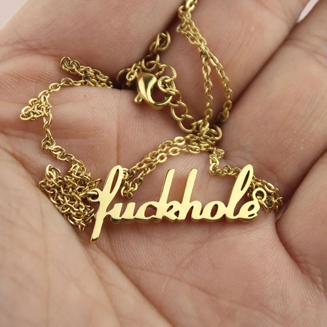The fuckhole pendant is shown laying in the palm of a hand, this image shows the strong gold colouring.