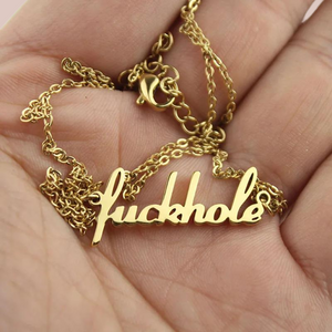 The fuckhole pendant is shown laying in the palm of a hand, this image shows the strong gold colouring.
