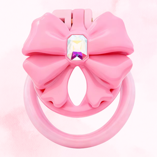 The pink chastity cage shown fully assembled on a soft pink background