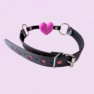 A rear view of the black gag with read heart detailing, silver hardware and pink heart shaped gag.