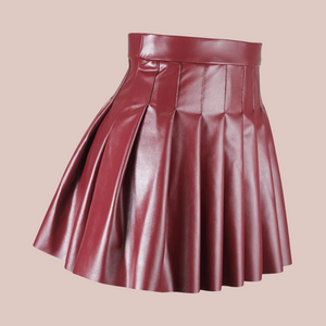 An angled view of the burgundy  high waisted PU Leather skirt, showing that the pleats run the whole way round.