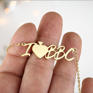 The I Heart BBC gold necklace from House Of Chastity is shown on an adult hand to give an idea of size.