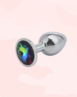 Jewelled anal plug with a multi-colour gemstone on a light pink background