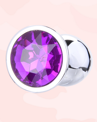 Jewelled Butt Plug with a purple gemstone on a pink background