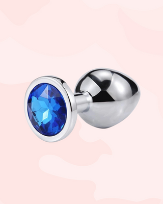 Jewelled anal plug with a blue gemstone on a pink background