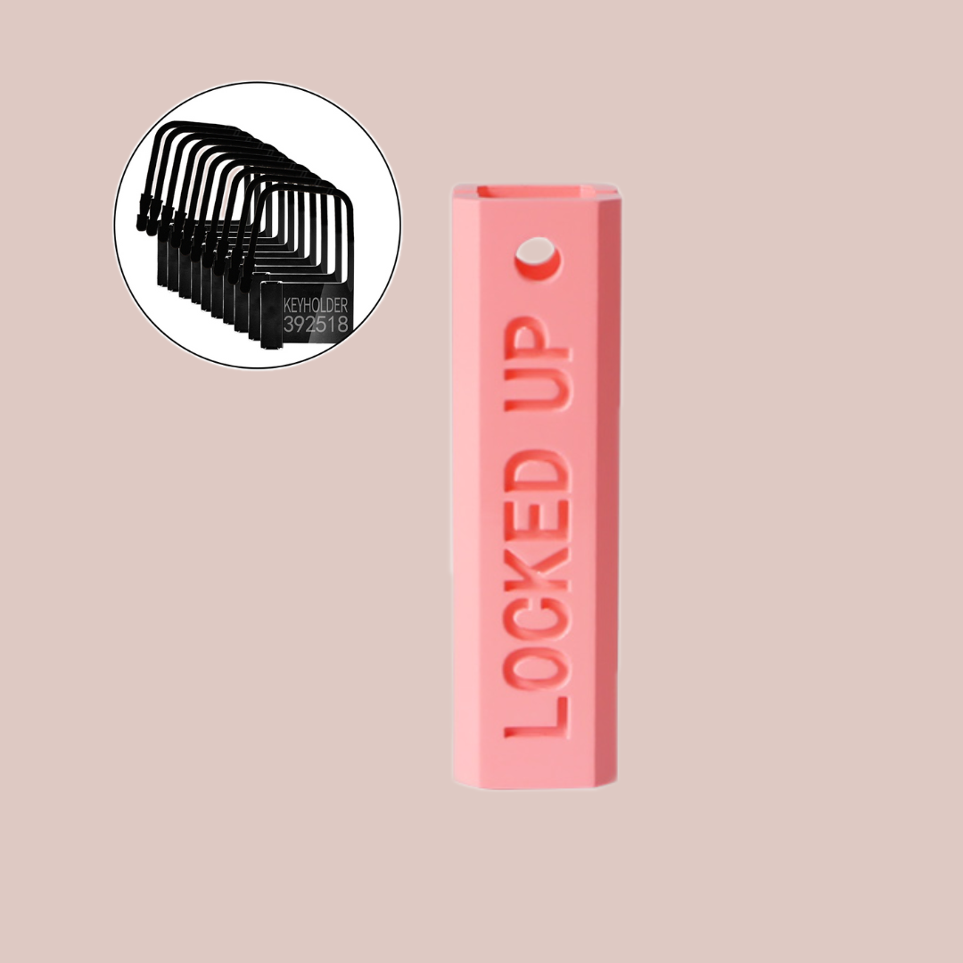 A close up of the Locked Up Chastity Cage Key Safe, in pink plastic with engraved wording, you can lock 1 key up. It also shows the plastic keyholder locks that come with the device.