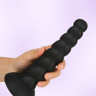 the large dildo is shown being held in front of a purple background