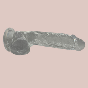 A side profile of the clear silicone dildo, the shaped head, veined body, large glans and suction cup base are all clear to see.
