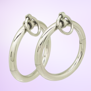 The silver Sub Rosa Locking Bracelet cuffs on a purple background.