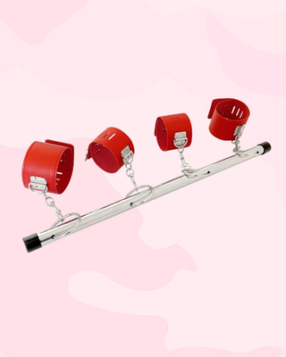 The red wrist and ankle cuffs attached to the fixed spreader bar, the snap hook attachments can be clearly seen.