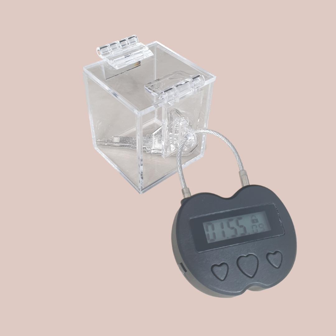 Showing the clear chastity key safe box, where you can see your chastity cage keys locked away nice and tight and you can't get to them. Also shown is the electronic lock that can be set on a timer for release.