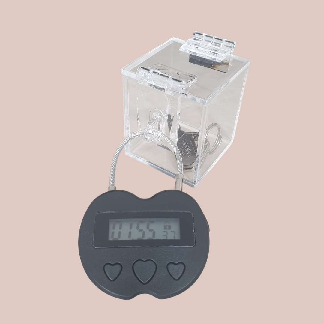 Showing the clear chastity key safe box, where you can see your chastity cage keys locked away nice and tight and you can't get to them. Also shown is the electronic lock that can be set on a timer for release.