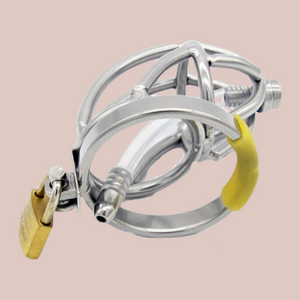 Shown laying on its side, A metal penis cage made from stainless steel, this is an open bar work design, with lines of steel meeting up to a a rounded open metal work head design. This cage has a hinge which allows the cage to move and an integral lock that fixes thecae to the base ring. There is also a urethral tube that can be removed.