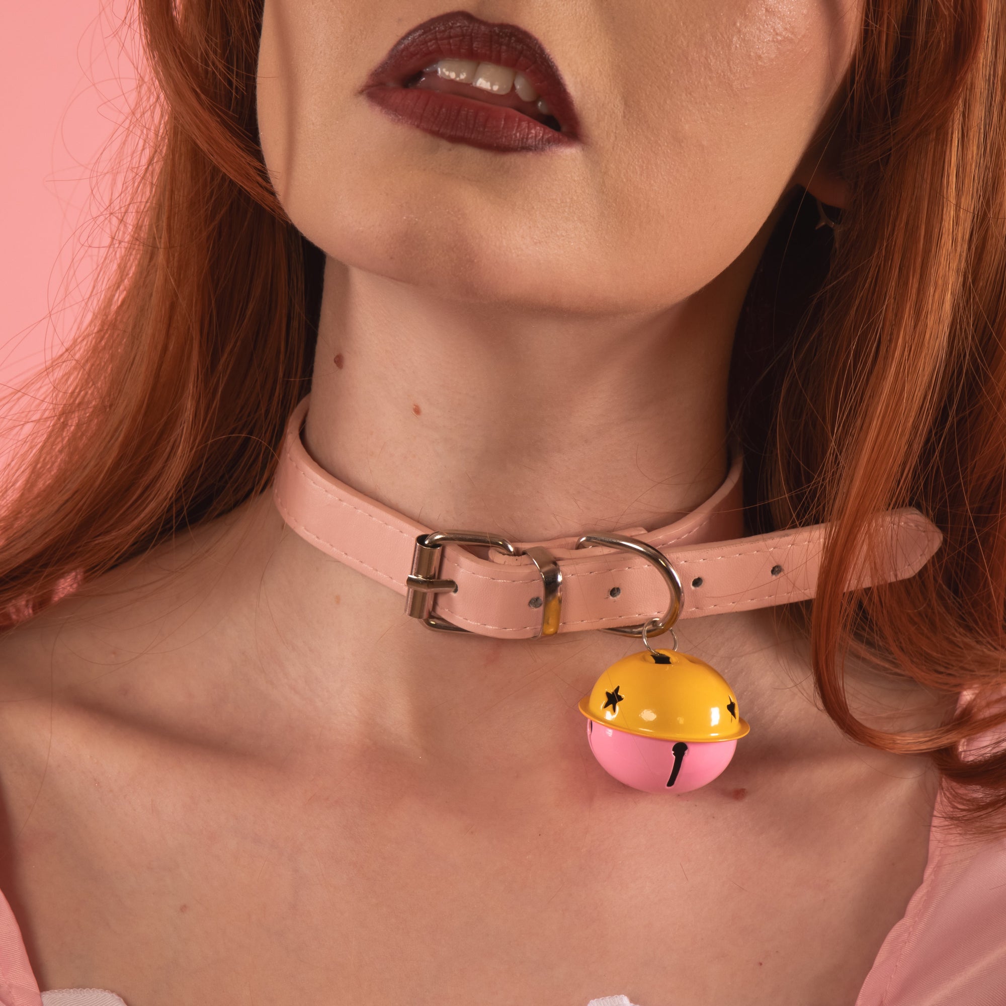 A close up of the collar with pink and yellow bell