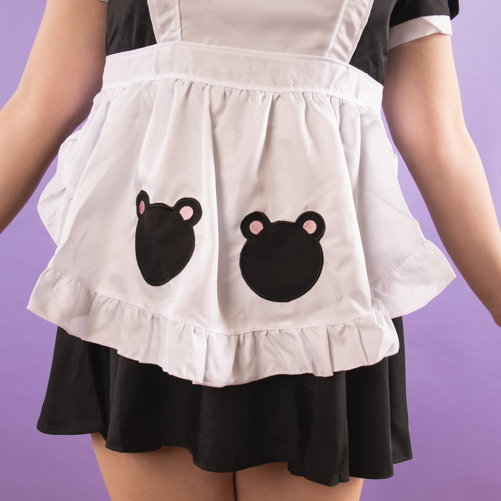 A close up of the apron skirt, it has decorative bear badges embroidered into the front.