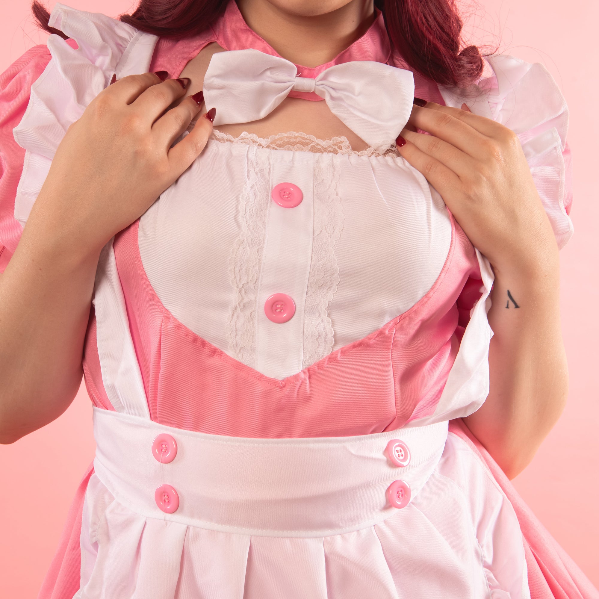 A close up of the front detailing to the Tilly Maid Dress, you can see the neck bow, lace and button detailing to the bust and removable apron.