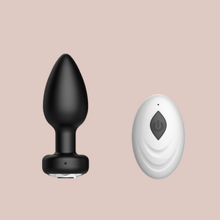 The black vibrating butt plug shows its jewelled base and the small remote control that comes with it.