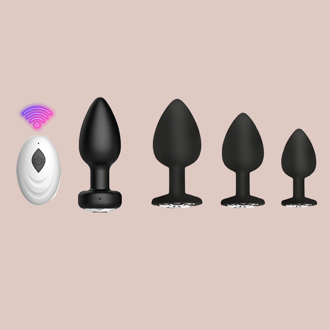 The image shows the vibrating anal plug with its remote control and the three other non vibrating anal plugs in small, medium and large. They are black with a diamond style crystal base gem stone.