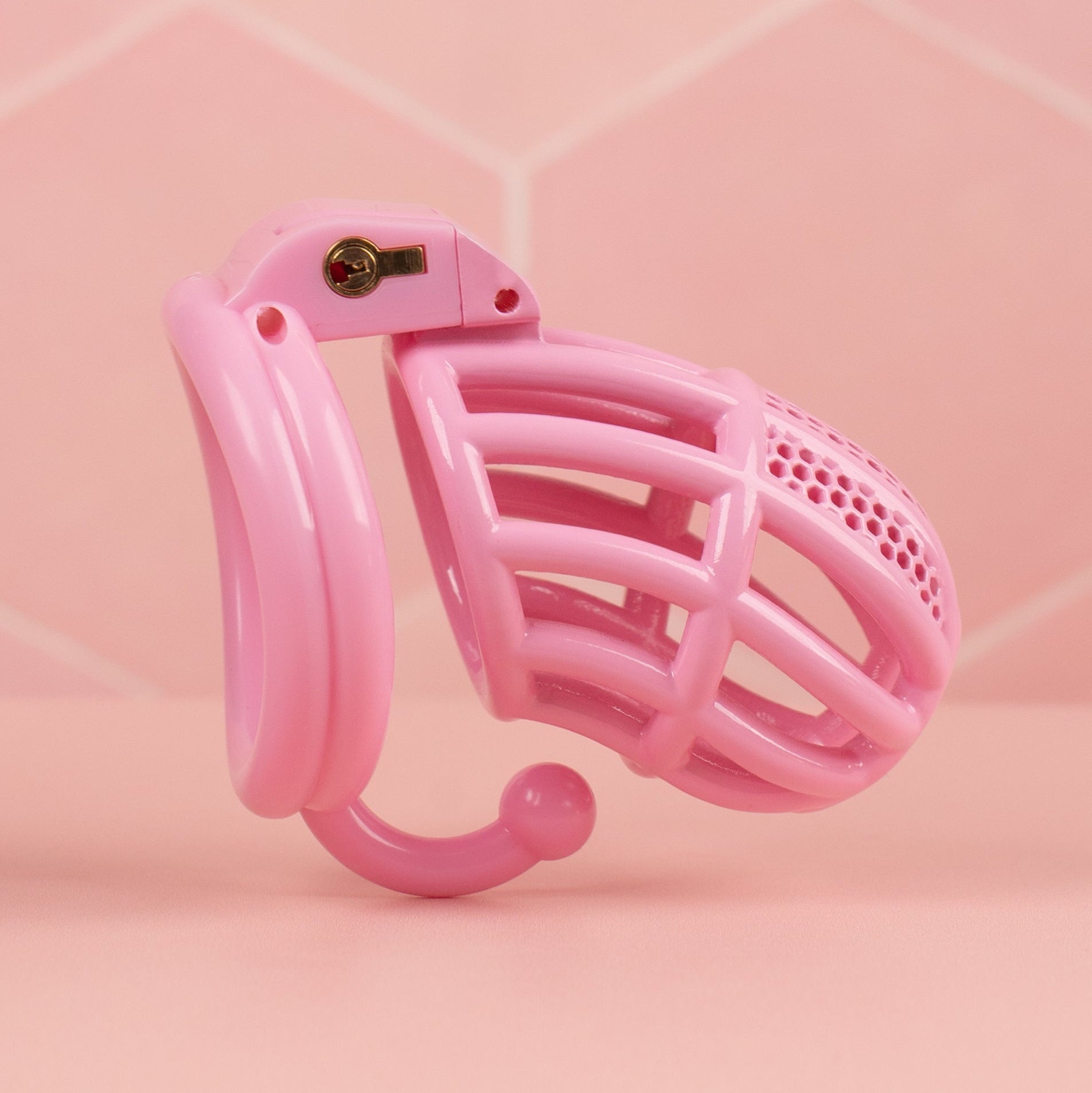 an alternate angle of The Detained standard size chastity cage in pink, from this angle you can see the integral lock fixed in place.