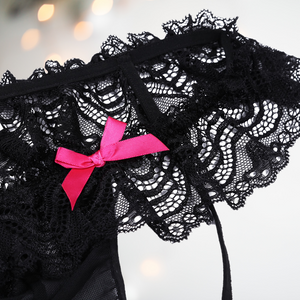 Close up of low rise hip style knickers with deep lace skirt, penis pouch and two decorative pink bows.
