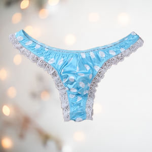 A soft blue satin men's female style knickers. They have a white spot pattern on the blue fabric, white lace edging to the legs and a thong style back.